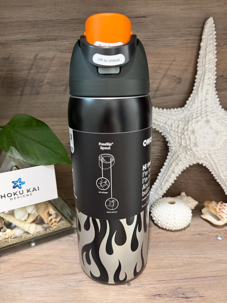 May include: A black and silver water bottle with an orange cap. The bottle has a flame design and the text "FreeSip Spout". The cap says "Lift to Unlock". The bottle is 32 oz.