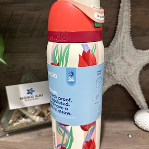 May include: A white insulated water bottle with a red and pink lid, featuring a floral design with red tulips. The bottle has a straw and is labeled "awala". The bottle is leak proof and insulated.