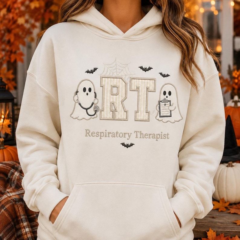May include: A cream-colored hooded sweatshirt featuring an embroidered design with two ghosts, one holding a stethoscope and the other a clipboard, flanking the letters RT. Above is a spiderweb and bats, with the text Respiratory Therapist below.