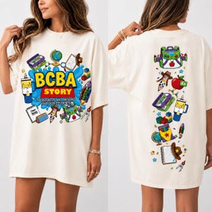 May include: An off-white t-shirt featuring a graphic print of school supplies and toys. The front displays the text BCBA STORY TO INFINITY AND BEYOND FOR OUR STUDENTS. The back features a vertical arrangement of colorful school-themed illustrations.