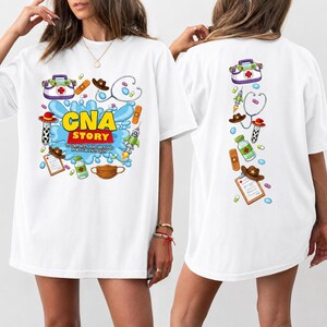 May include: A white t-shirt featuring a graphic print of medical supplies and cowboy-themed items. The front displays the text "CNA STORY TO INFINITY AND BEYOND FOR OUR PATIENTS" amidst a blue splash. The back shows a vertical arrangement of the same icons.