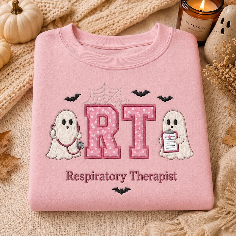 May include: A light pink crewneck sweatshirt featuring embroidered designs of two white ghosts, one holding a stethoscope and the other a clipboard. The letters RT are in pink with white polka dots, accompanied by a spiderweb, bats, and the text Respiratory Therapist.