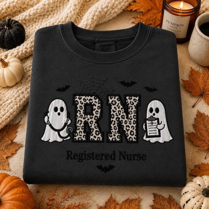 May include: A black crewneck sweatshirt featuring an embroidered design with two white ghosts, one holding a stethoscope and the other a clipboard. The letters RN are filled with a leopard print pattern. The text Registered Nurse is below.