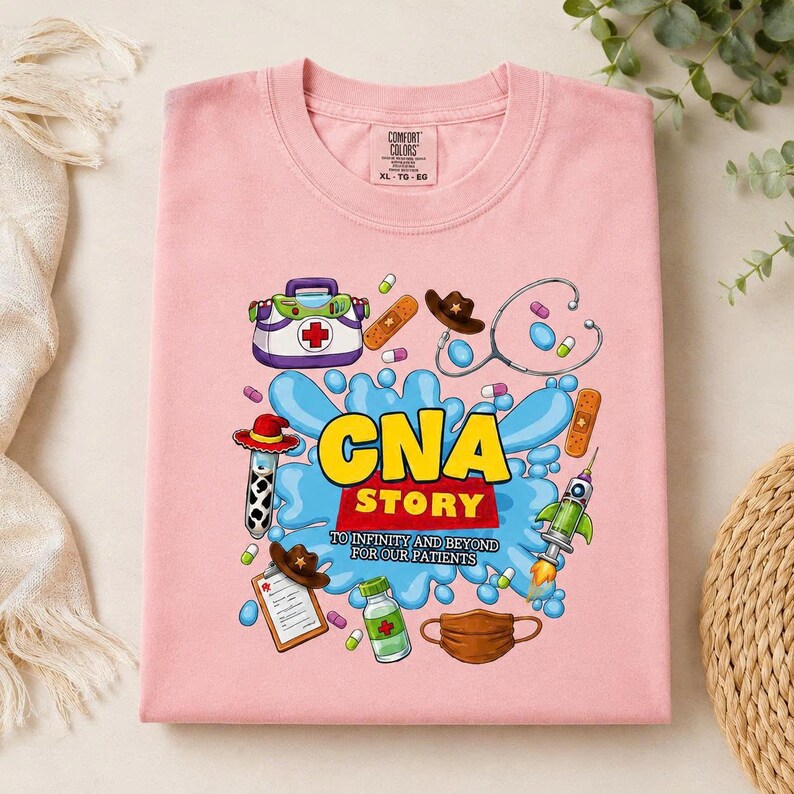 May include: A light pink t-shirt featuring a graphic print with the text CNA STORY TO INFINITY AND BEYOND FOR OUR PATIENTS. The design includes medical items like a stethoscope, a clipboard, a face mask, and pills, alongside toy-themed elements.