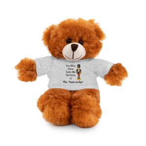 May include: A brown teddy bear wearing a gray t-shirt with the text "You May Have Seen Me Perform In The Nutcracker" and a graphic of a Nutcracker soldier. The bear has a light brown snout and dark eyes.