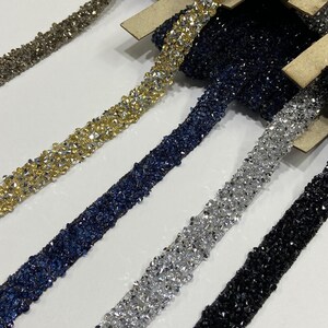 May include: Five spools of beaded trim in different colors. The trim is made of small, faceted beads in gold, silver, black, and blue.