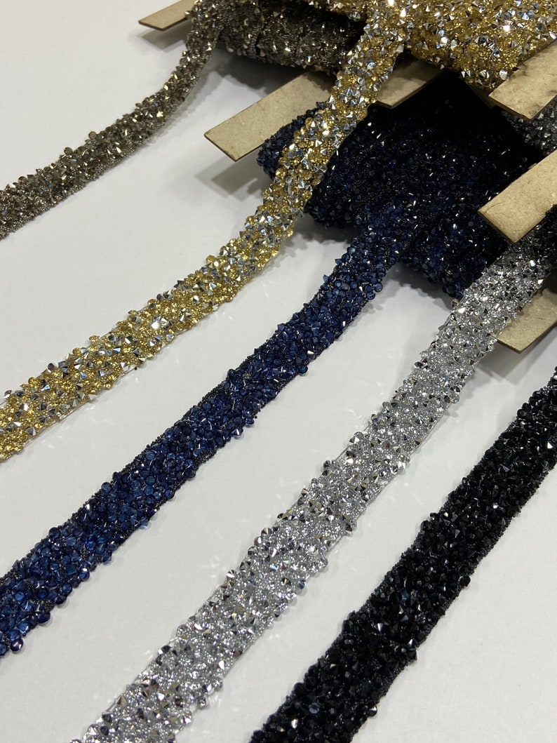 May include: Five spools of beaded trim in different colors. The trim is made of small, faceted beads in gold, silver, black, and blue.