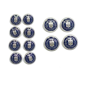 Puede incluir: Un conjunto de doce botones redondos con un centro de esmalte azul profundo y un emblema de escudo y corona en metal plateado. Cada botón está enmarcado por un borde plateado con textura de cuerda, creando una apariencia uniforme.