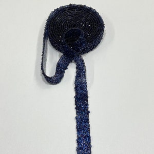 May include: A roll of dark blue beaded trim with a long strand of the trim hanging down.