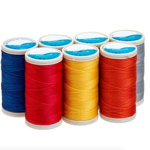 May include: Eight spools of Nylbond thread in a range of colours: blue, red, yellow, orange, and grey. Each spool has a white and blue label. The thread is tightly wound on cylindrical spools.