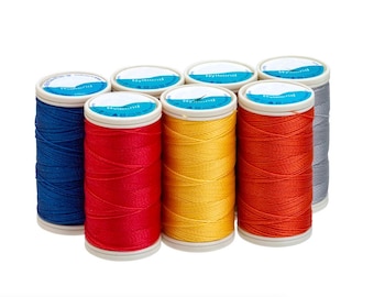 Op de afbeelding: Een verzameling van acht spoelen Nylbond-garen in verschillende kleuren, waaronder blauw, rood, geel, oranje en grijs. Elke spoel heeft een wit en blauw label. Het garen is strak op cilindrische spoelen gewikkeld.
