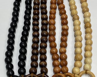 May include: Four wooden beaded straps with wooden rings at each end. The straps are in different shades of brown, black, and natural wood.