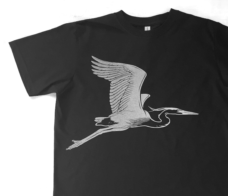 May include: A black t-shirt with a white silhouette of a heron in flight.