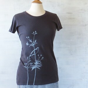 May include: A dark grey t-shirt with a light blue floral design on the left side.