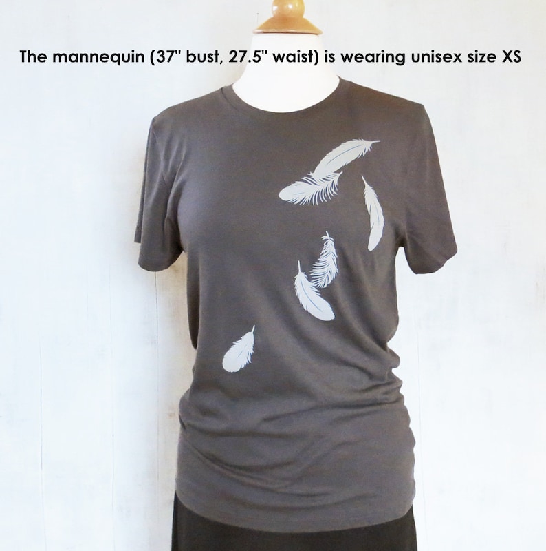 May include: A charcoal gray t-shirt with a white feather design. The mannequin is wearing a size XS.