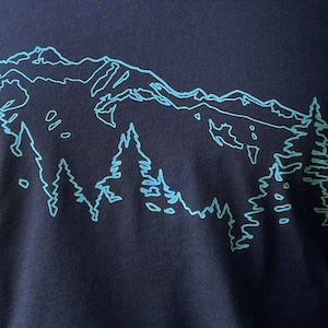 May include: A navy blue t-shirt with a light blue outline of a mountain range and trees.