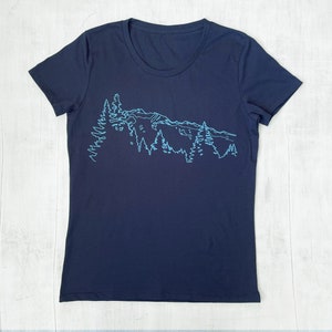 May include: A navy blue t-shirt with a light blue outline of a mountain range and trees.
