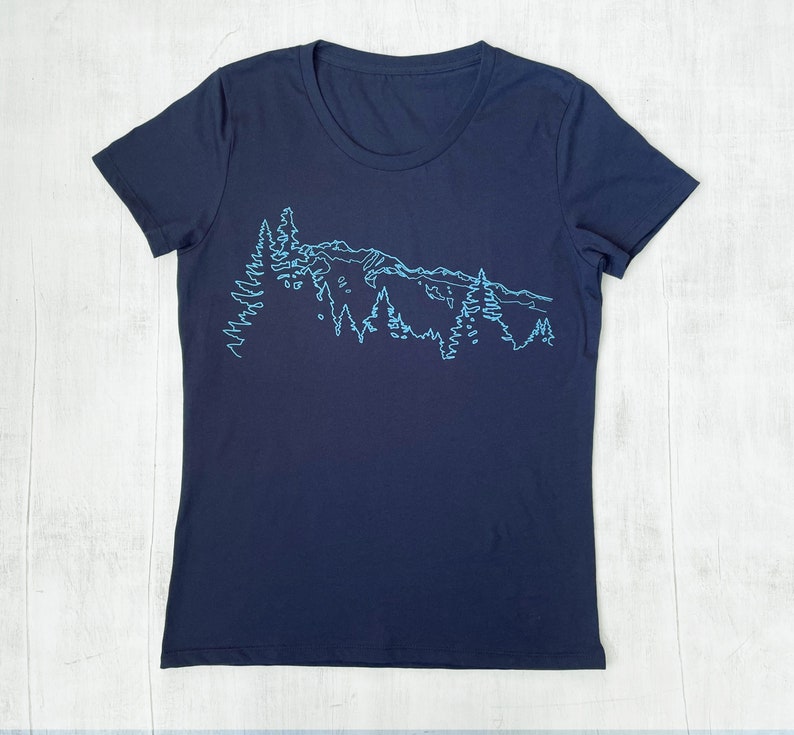 May include: A navy blue t-shirt with a light blue outline of a mountain range and trees.