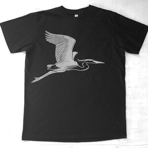 May include: A black t-shirt with a white silhouette of a heron in flight.