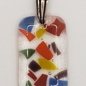 May include: A white glass pendant with a silver bail. The glass is filled with colorful confetti-like pieces of glass in red, orange, yellow, green, blue, and purple.