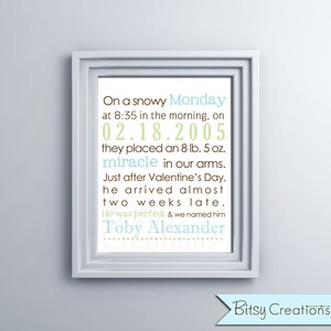 May include: A framed print with a light blue background and white text. The text reads "On a snowy Monday at 8:35 in the morning, on 02.18.2005 they placed an 8 lb. 5 oz. miracle in our arms. Just after Valentine's Day, he arrived almost two weeks late. He was perfect & we named him Toby Alexander."