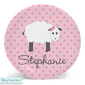 May include: A pink and white personalized plate with a white sheep with a pink bow and the name Stephanie.