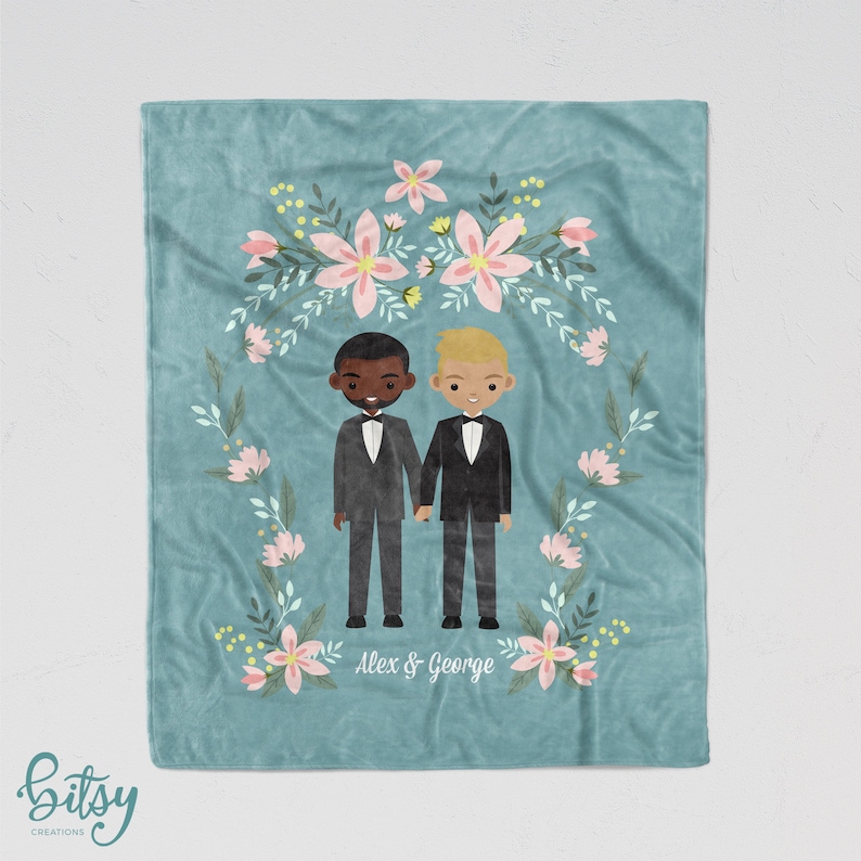 May include: A teal blue fleece blanket with a floral wreath design. Two cartoon figures of grooms in black tuxedos stand in the center of the wreath. The text "Alex & George" is printed below the figures.