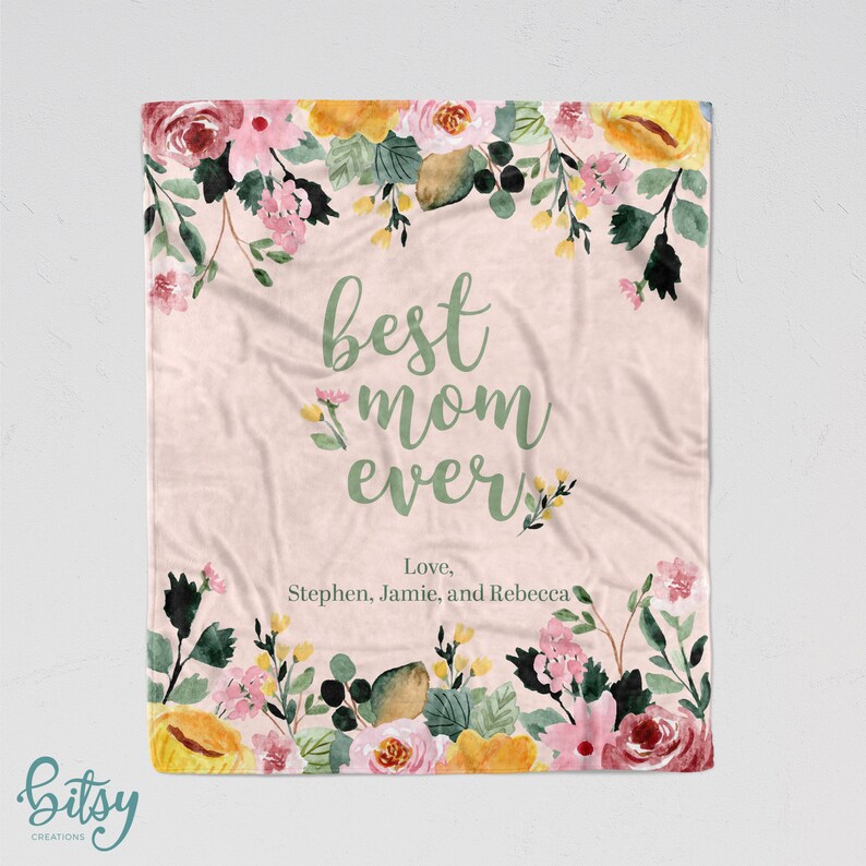 Pu&ograve; includere: Una coperta in pile rosa con motivo floreale e il testo "best mom ever" in corsivo verde. Il testo "Love, Stephen, Jamie, and Rebecca" &egrave; scritto sotto il testo principale.