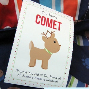 May include: A white card with green and red polka dots around the border. The card says "You found COMET" in red letters. A cartoon reindeer with a green collar is pictured on the card. The card also says "Hooray! You did it! You found all of Santa's missing reindeer!" and "Bitsy Creations" in blue letters.
