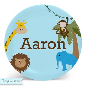 May include: A blue personalized plate with a giraffe, lion, monkey, and elephant. The plate says "Aaron" in brown letters.