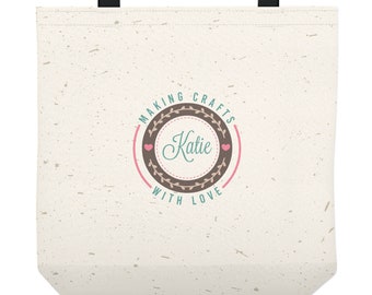 May include: A beige tote bag with a brown circle design that says "Making Crafts with Love" and "Katie" in a teal script font. There are two pink hearts on either side of the name.