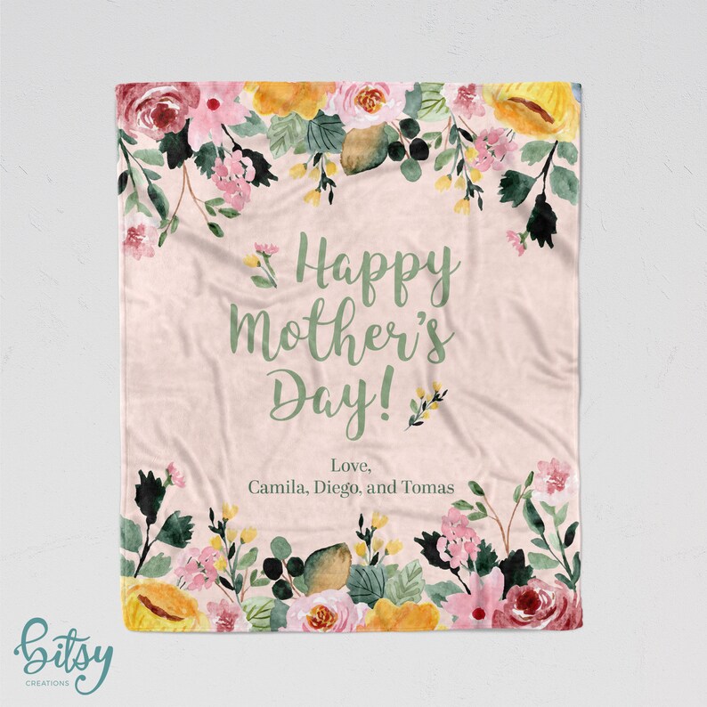 Pu&ograve; includere: Una coperta rosa con motivo floreale e il testo "Happy Mother's Day! Love, Camila, Diego, and Tomas" in lettere verdi.