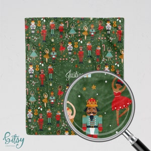 May include: A green fleece blanket with a repeating pattern of nutcracker soldiers and ballerinas. The blanket has the name "Justice" printed on it.