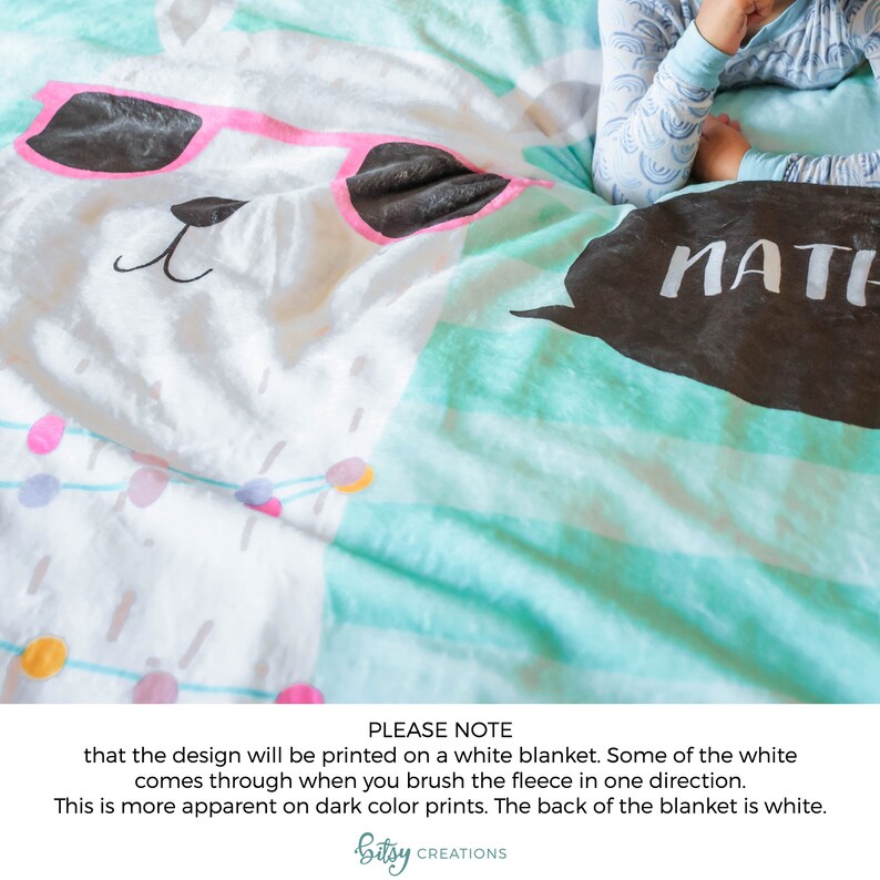 May include: A white fleece blanket with a llama wearing pink sunglasses and a black speech bubble with the word "MATH" printed on it. The blanket has a turquoise and white striped pattern.