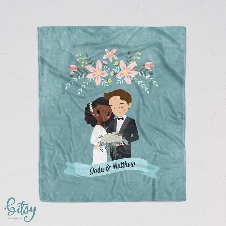 May include: A teal blue fleece blanket with a floral design and a cartoon illustration of a bride and groom. The bride is Black and the groom is white. The text "Jada & Matthew" is on a white ribbon.