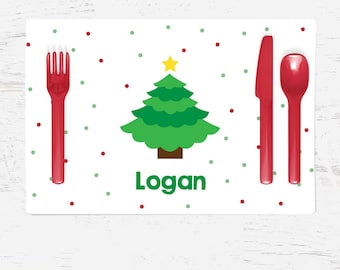May include: A white Christmas-themed placemat with red and green polka dots. A green Christmas tree with a yellow star is in the center. The placemat has the name "Logan" printed on it. Red plastic cutlery is included.