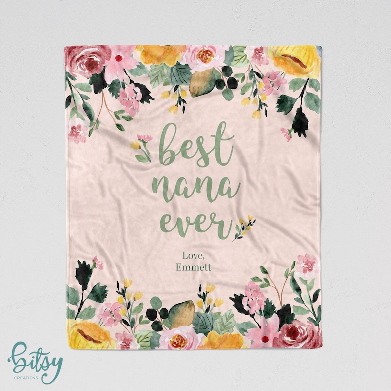 Pu&ograve; includere: Una coperta rosa con motivo floreale e il testo "best nana ever" in lettere verdi. Il testo "Love, Emmett" &egrave; scritto sotto il testo principale.