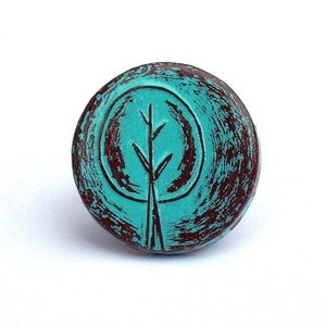 May include: A round turquoise and brown ceramic knob with a stylized tree design.