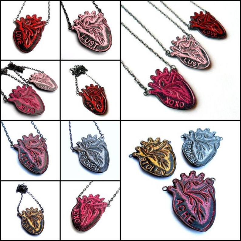 May include: A collection of heart-shaped pendant necklaces in various colors, including red, pink, and gold. Each pendant features an anatomical heart design with words like "LOVE," "LUST," and "BROKEN." The necklaces have silver chains.