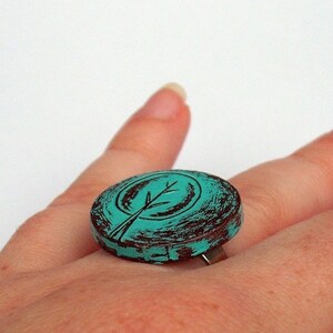 May include: Teal blue ring with a brown distressed finish. The ring features a stylized tree design.