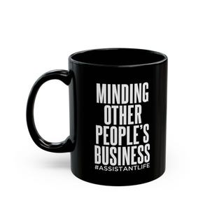 Könnte beinhalten: Schwarze Kaffeetasse mit weißem Text, der "Minding Other People's Business #AssistantLife" lautet.