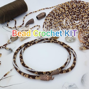 Peut inclure: Texte KIT de crochet de perles en couleurs arc-en-ciel. L'image présente un collier de perles enroulé avec des perles marron, blanches et beiges. Des perles, des fermoirs et du fil supplémentaires sont disposés autour du collier. Le kit comprend tous les matériaux nécessaires.