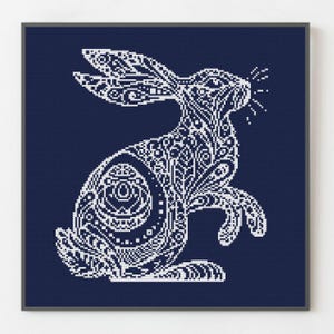 May include: A white rabbit with a detailed, intricate pattern on a dark blue background. The rabbit is in a standing position with its ears up and its tail behind it.