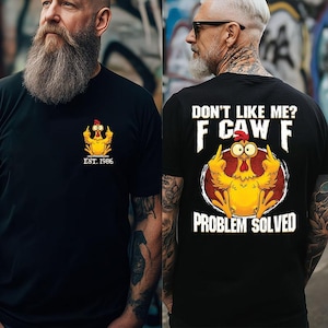 May include: Black t-shirts with a humorous chicken graphic. One shirt features a small chicken design with "EST. 1986". The other shirt has a larger chicken graphic with the text "DON'T LIKE ME? F CAW F PROBLEM SOLVED".