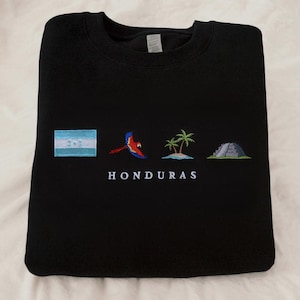 May include: Black sweatshirt with embroidered Honduran flag, parrot, palm trees, and Mayan ruins. The text "HONDURAS" is embroidered below the images.