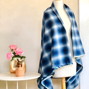May include: A blue and white plaid shawl with a white trim. The shawl is draped over a mannequin.