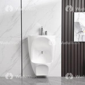 May include: A white wall-mounted urinal with a chrome faucet and two chrome soap dispensers. The urinal is in a bathroom with white marble tiles and a brown wood-paneled wall.