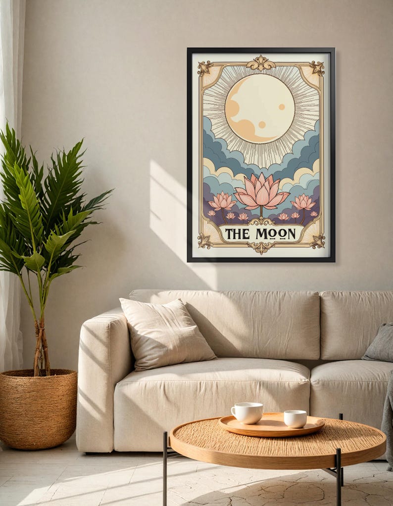 May include: A vintage-style tarot card illustration of The Moon card. The card features a full moon with rays of light, clouds, and three pink lotus flowers. The text "THE MOON" is printed in a decorative font at the bottom of the card.