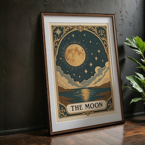 Op de afbeelding: Een ingelijste print van een vintage-stijl illustratie van de maan, sterren en een meer. De maan is vol en geel, en het meer is blauw met een reflectie van de maan. De print is omgeven door een gouden lijst met sierlijke details. De tekst "THE MOON" is in gouden letters gedrukt aan de onderkant van de print.