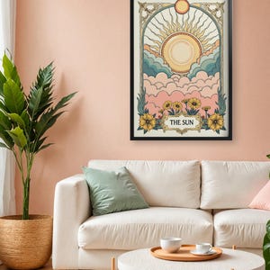 May include: A black framed print with a vintage illustration of the sun shining over clouds. The illustration is in a pastel color palette with yellow, pink, blue, and green. The text "THE SUN" is at the bottom of the print.